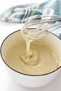 Roux for cooked milk frosting on a whisk.