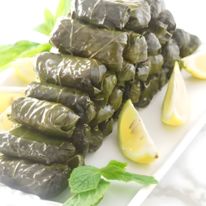 Stuffed grape leaves with rice, garnished with lemon wedges and mint.