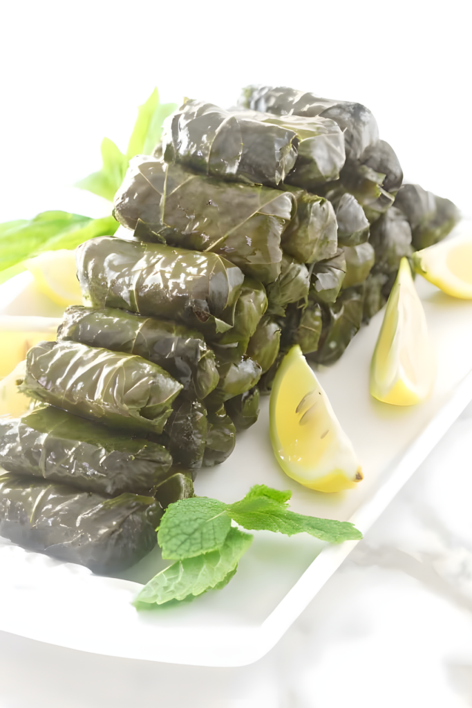 Stuffed grape leaves with rice, garnished with lemon wedges and mint.