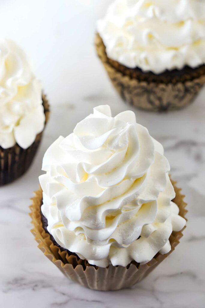 A cupcake with Italian meringue buttercream swirled on top.