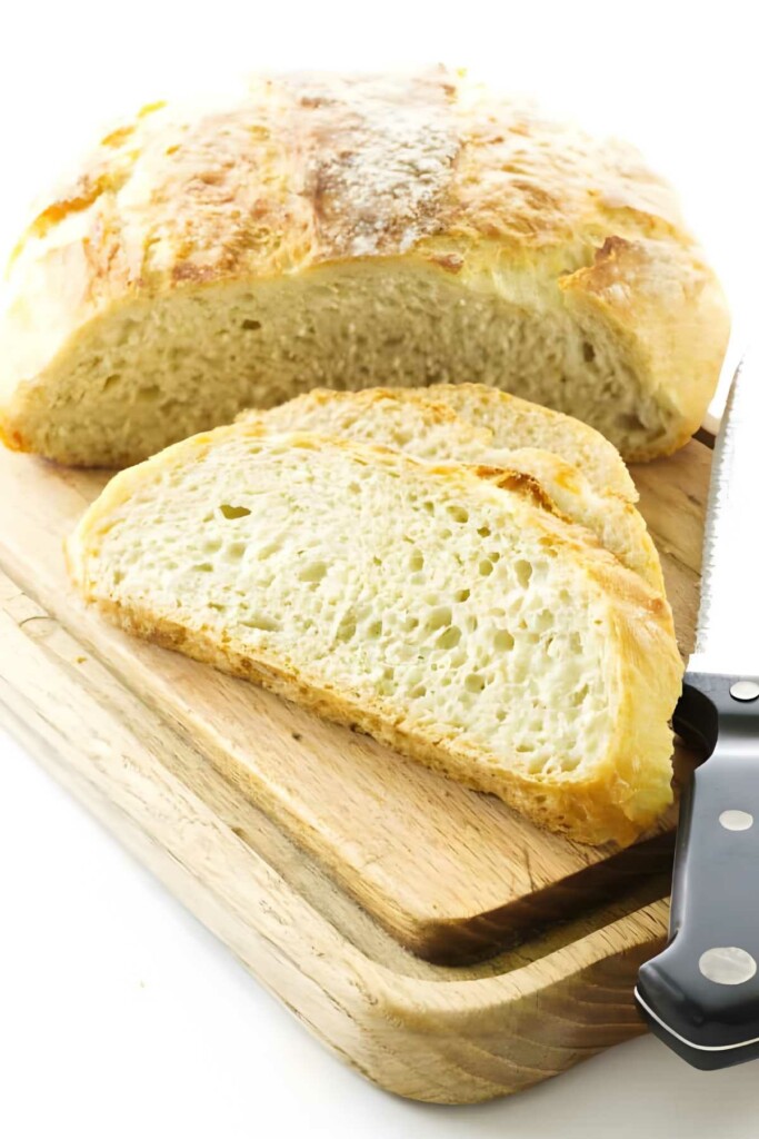 Sliced rustic bread on wooden board.