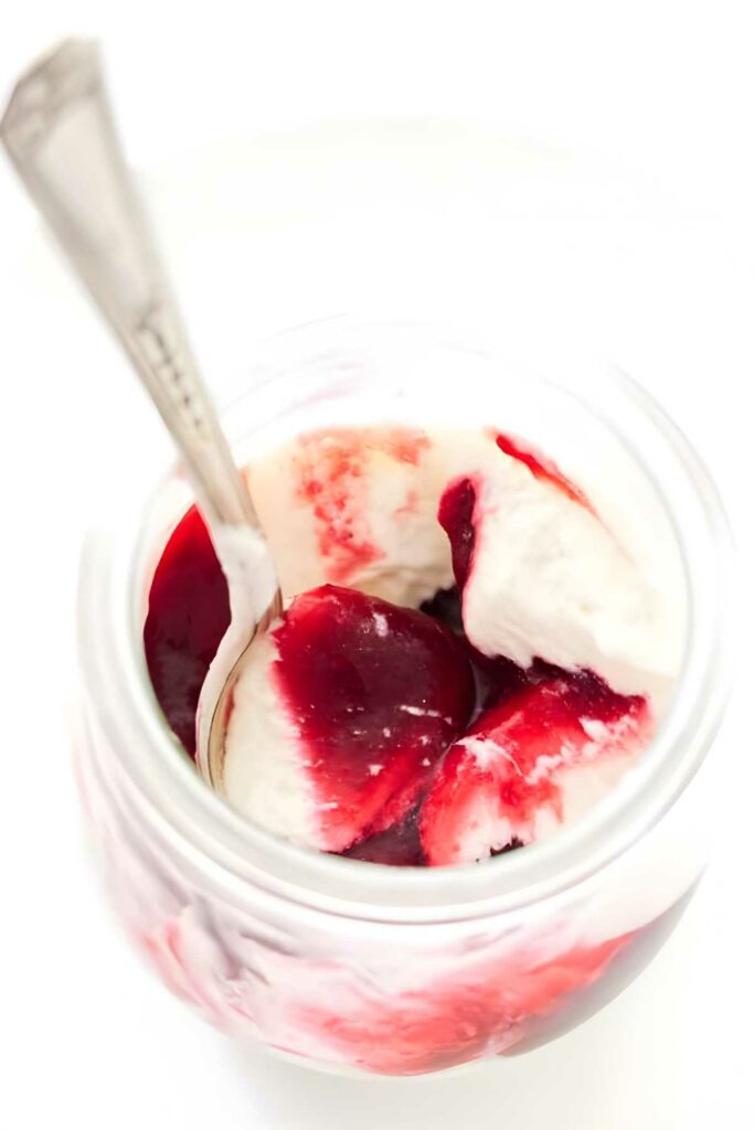 A spoon in a dish of raspberry white chocolate moussse.