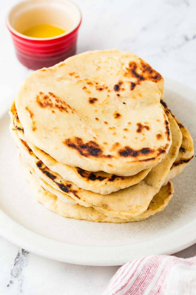A stack of sourdough discard flatbread with a dish of butter in the background.