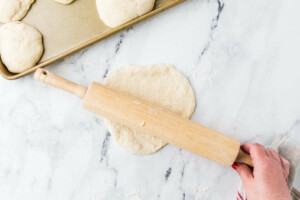 A rolling pin rolling flatbread sourdough rounds.