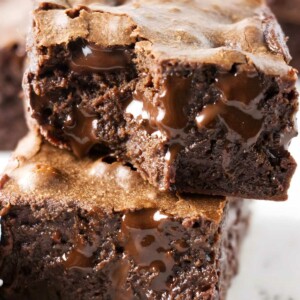Two stacked fudgy chocolate brownies with melted chocolate oozing from center.