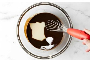 Hand holding whisk stirring in Eagle brand condensed milk.