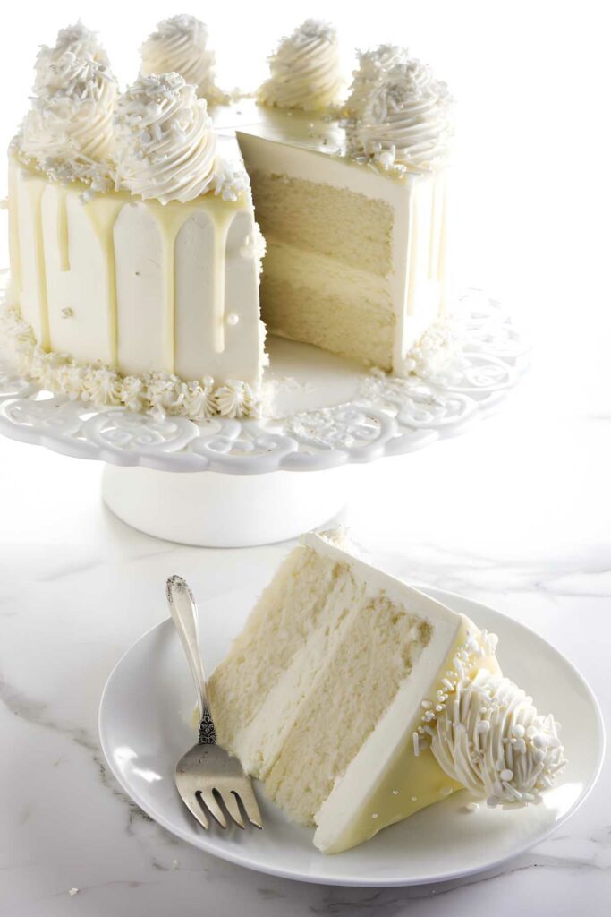 White frosted layer cake with slice served on plate; elegant white icing.