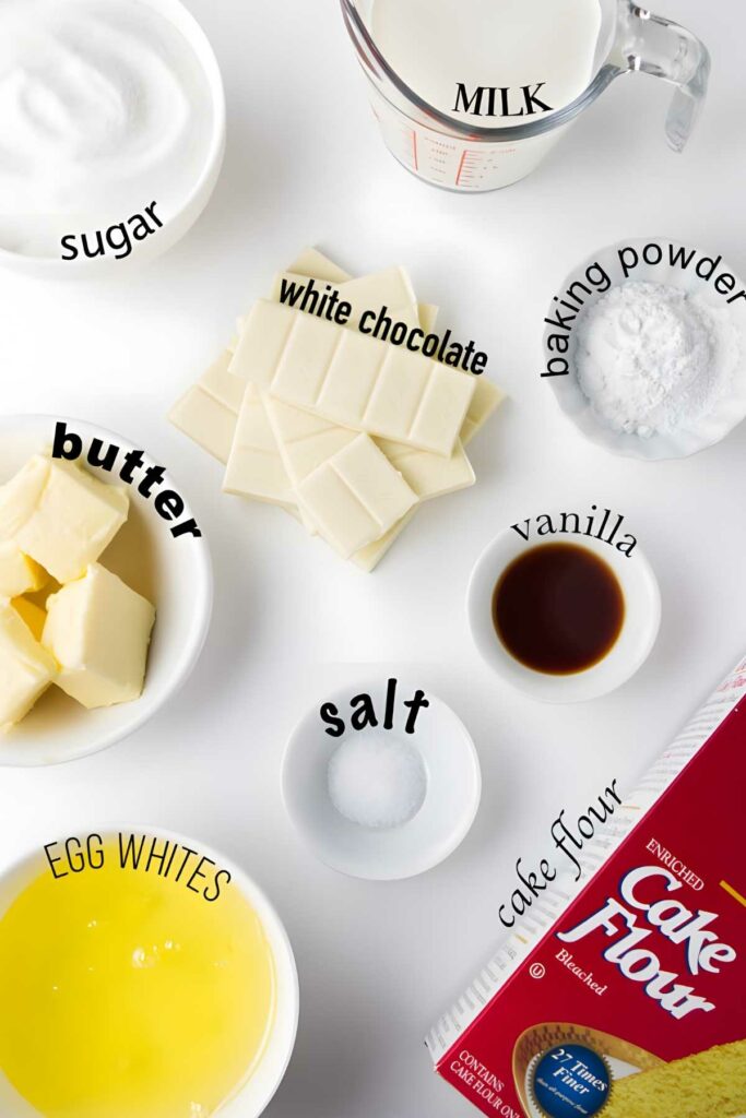 Overhead shot: labeled cake ingredients arranged on a white surface.