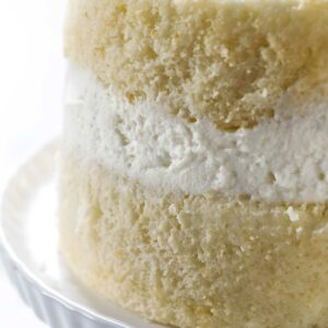 Close-up of partially frosted layer cake with white cream filling.