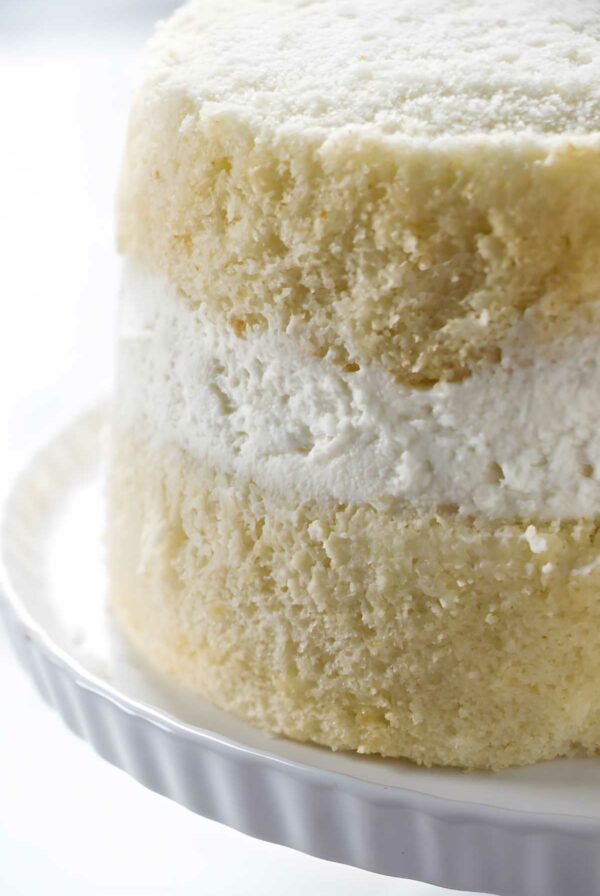 Close-up of partially frosted layer cake with white cream filling.