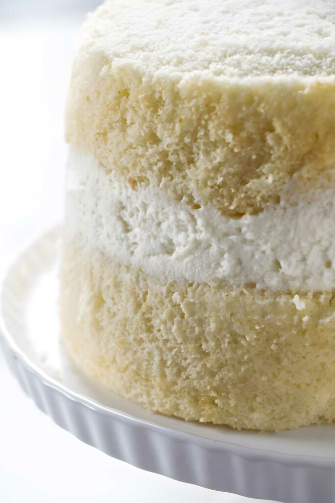 Close-up of partially frosted layer cake with white chocolate cream filling.