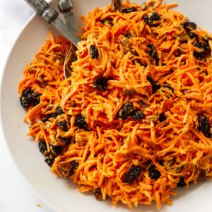 A bowl filled with carrot raisin salad.