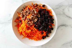 Shredded carrots and raisins and nut in a bowl.