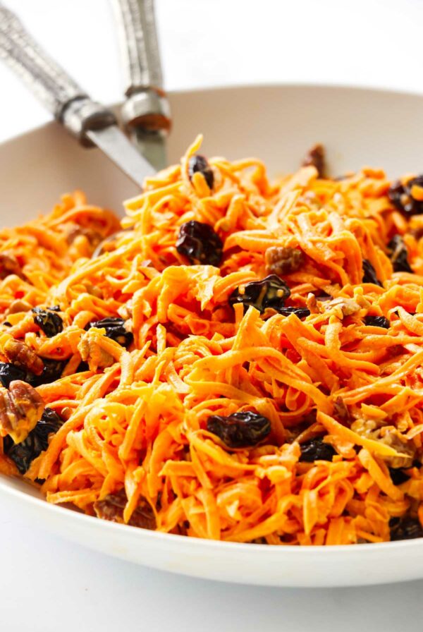 A simple carrot salad with raisins in a white bowl.