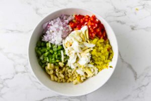 Combining all the ingredients for a mac salad in a large bowl.