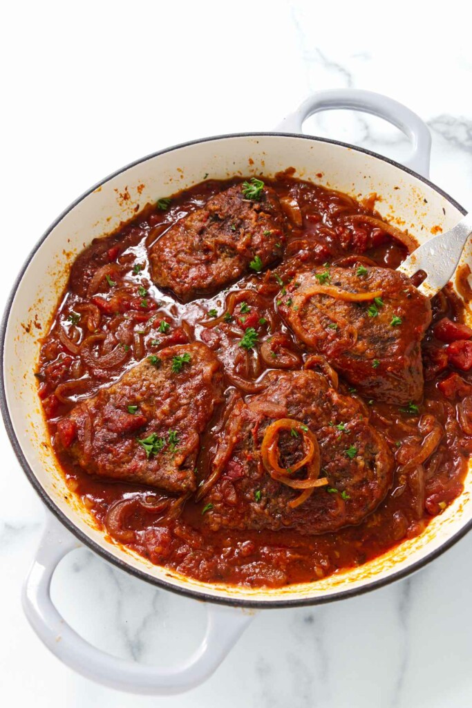 A steak and tomatoes recipe in a large skillet.
