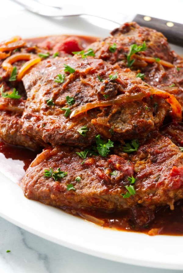 A large platter filled with steak and tomatoes.