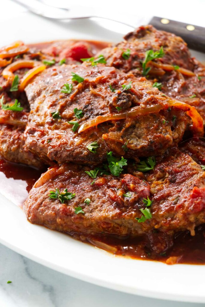 A large platter filled with steak and tomatoes.