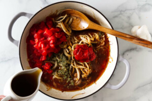Adding tomatoes and broth to the skillet for a tomato steak recipe.
