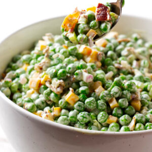 A spoon lifting a serving of pea and cheese salad.