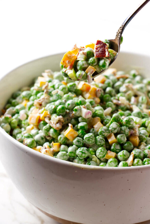 A spoon lifting a serving of pea and cheese salad.