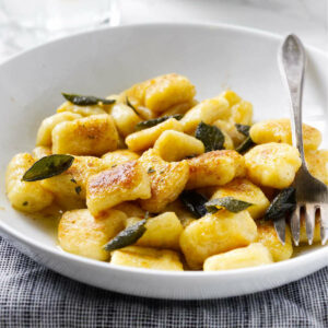 A bowl of pillowy ricotta gnocchi covered in sage brown butter.
