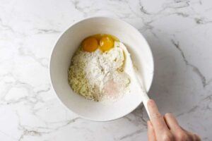 Stirring eggs, flour, and salt into ricotta gnocchi dough.