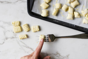 Rolling gnocchi down a fork to make ridges.