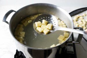 boiling gnocchi and scooping Italian dumplings out of the water.
