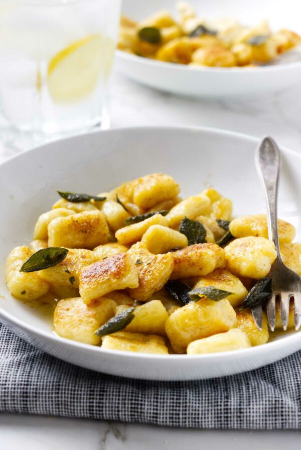 Pillowy gnocchi made with fresh ricotta in a bowl and topped with sage butter.