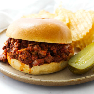 Sloppy joes from scratch on a hamburger bun next to potato chips.