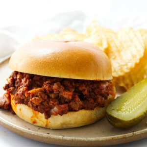 Sloppy joes and potato chips on a lunch plate.