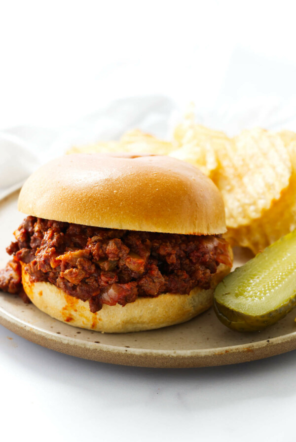 Sloppy joes and potato chips on a lunch plate.