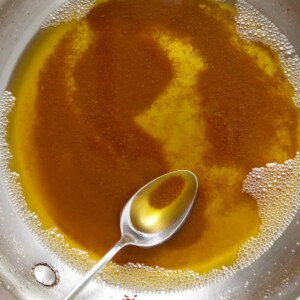 A spoon in a pan with golden brown butter.