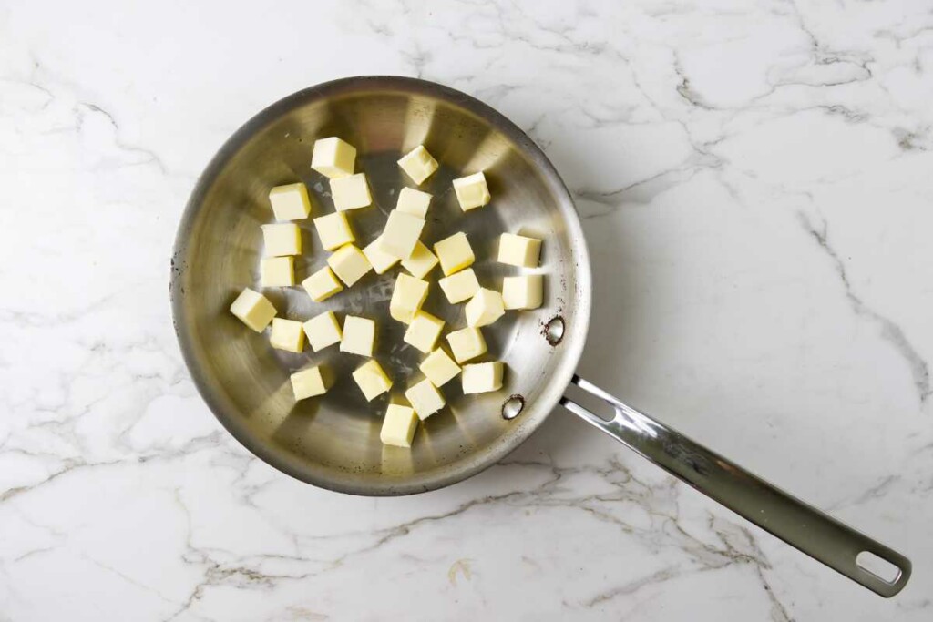 Cubes of butter in a stainless steel skillet.
