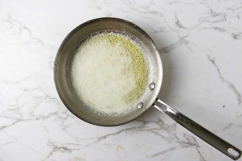 Melted butter in a skillet with foam on top.