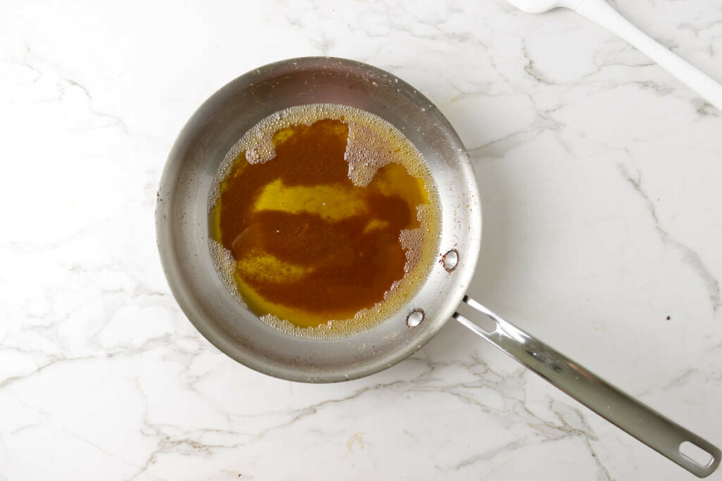 Browned butter in a skillet showing the brown milk solids.