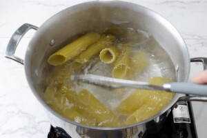 Boiling manicotti pasta in water.
