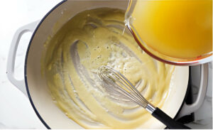 Pouring chicken broth into the skillet to make enchilada sauce.