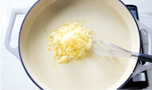 Stirring cheese into sauce in a skillet.