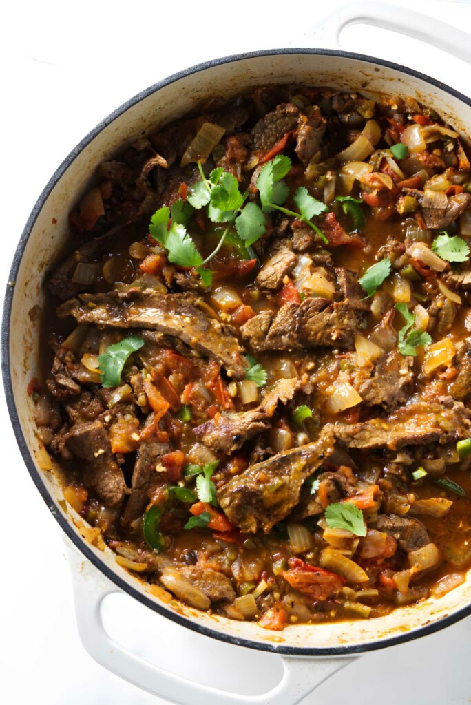 Beef ranchero in a white skillet.