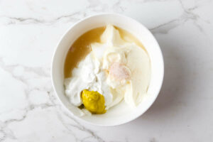 Mixing mayonnaise and sour cream to make a dressing for pea salad.