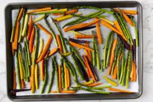 Roasting a carrots and asparagus recipe on a baking sheet.