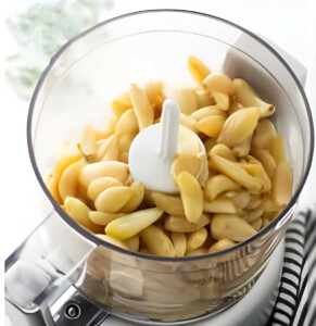 Placing the roasted garlic in a food processor to make a smooth spread.