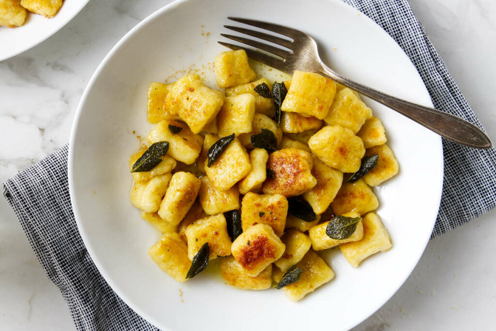 A pasta dish filled with gnocchi topped with sage brown butter sauce.
