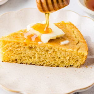 Drizzling honey on top of a slice of sourdough cornbread.