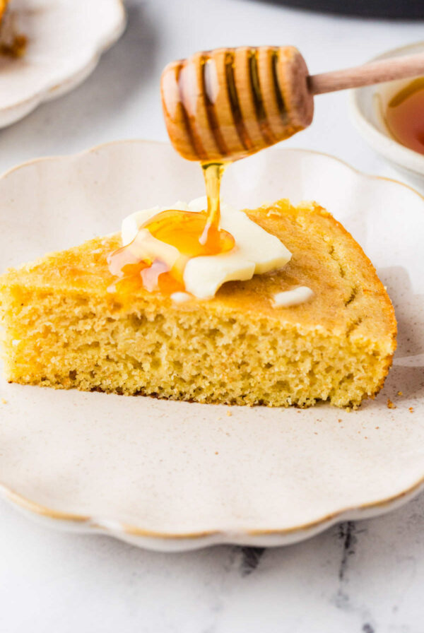 Drizzling honey on top of a slice of sourdough cornbread.