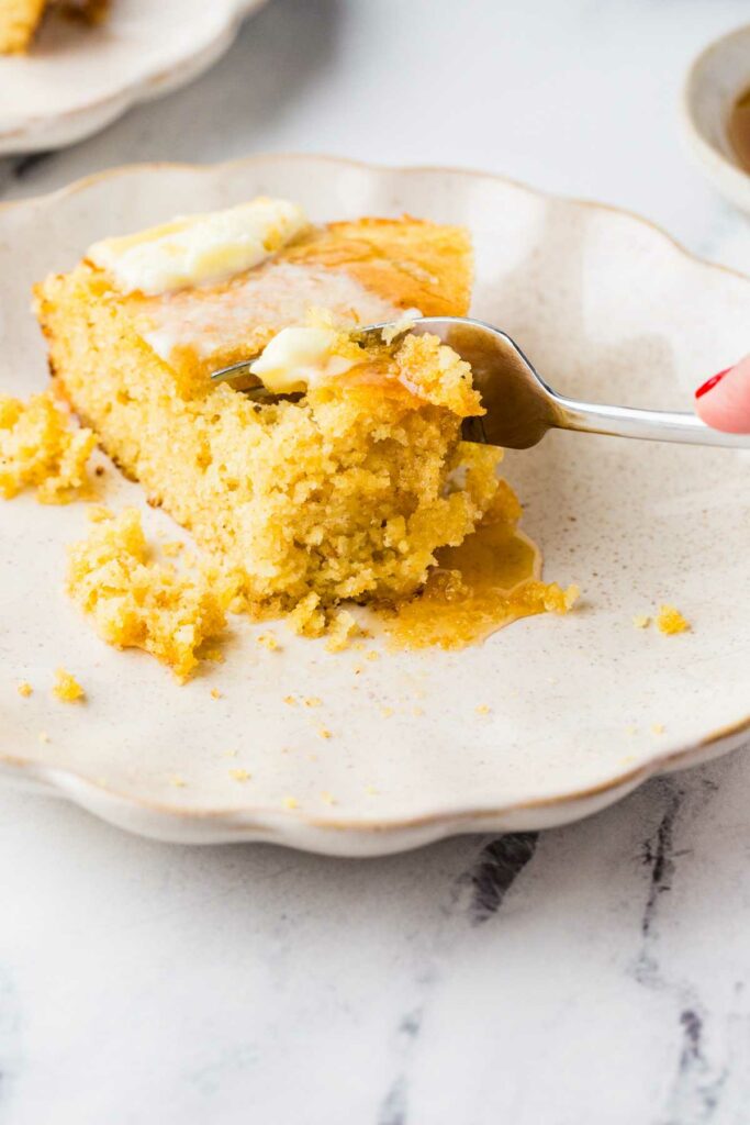A fork taking a bite from a slice of discard cornbread.
