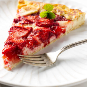 A strawberry galette with a cheesecake bottom next to a fork.