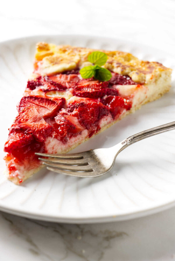 A strawberry galette with a cheesecake bottom next to a fork.